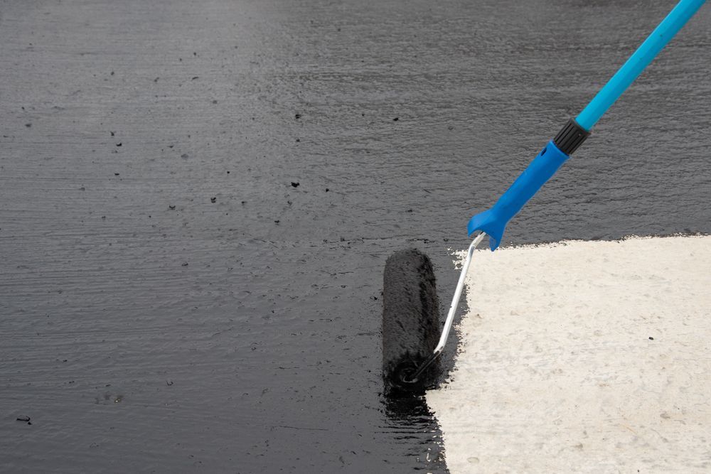 A Person is Painting a Concrete Surface With a Roller — Anderson Tiling and Waterproofing in Whitfield, QLD