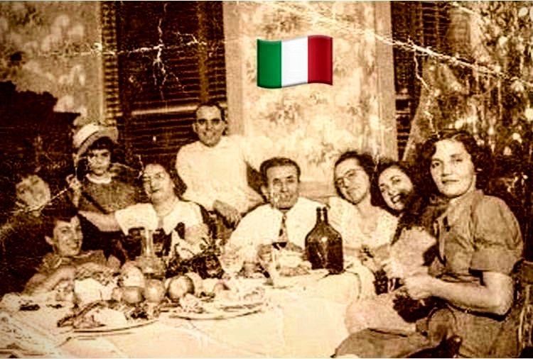 A group of people are sitting around a table with a flag in the background.