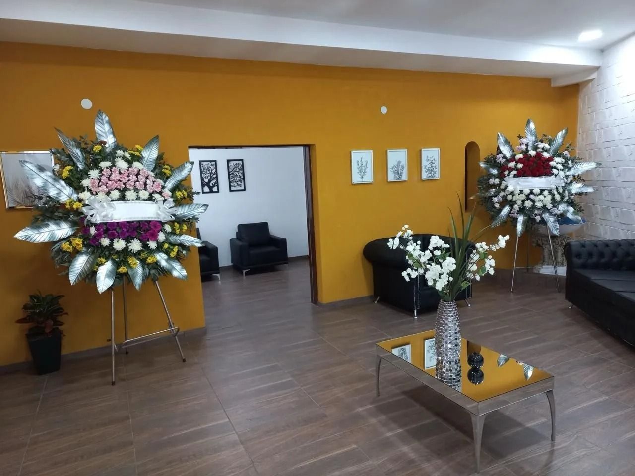 Interior vacío de la capilla con bancos de madera, arreglos florales y un altar central al frente.