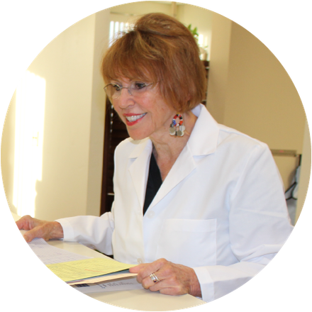 Dr. Roberta in a lab coat is sitting at a desk