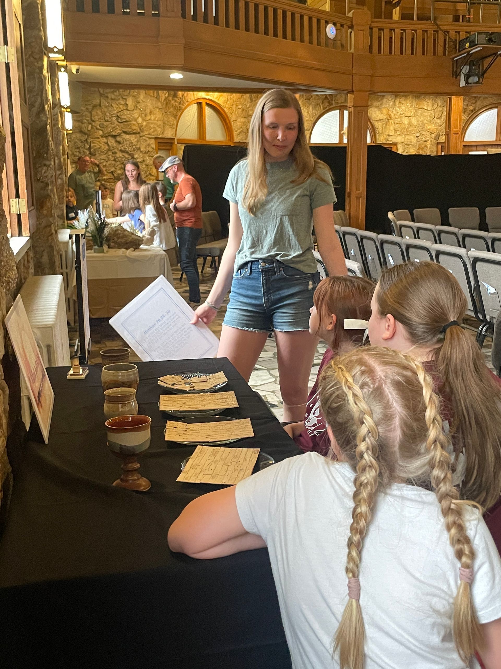 College student leading three children through a prayer station.