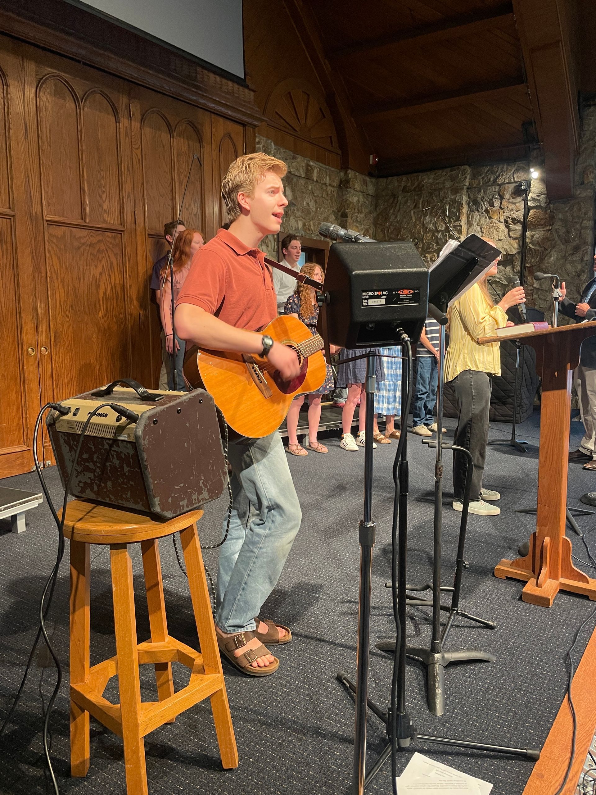 Musicians performing onstage with a singer playing guitar at a microphone.