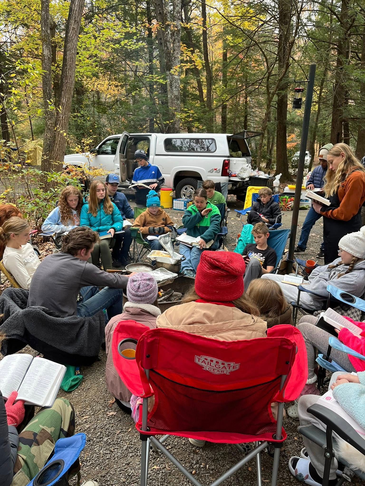 Group seated around a campfire doing a Bible study.