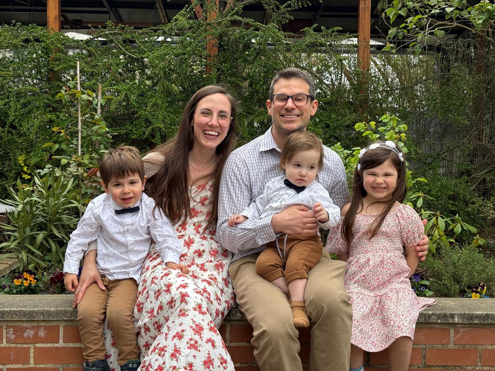 Family of five in front of greenery.