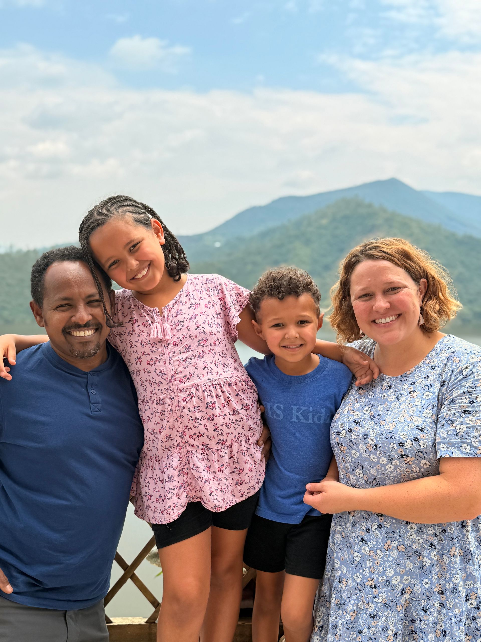 Family of four standing in front of mountains.