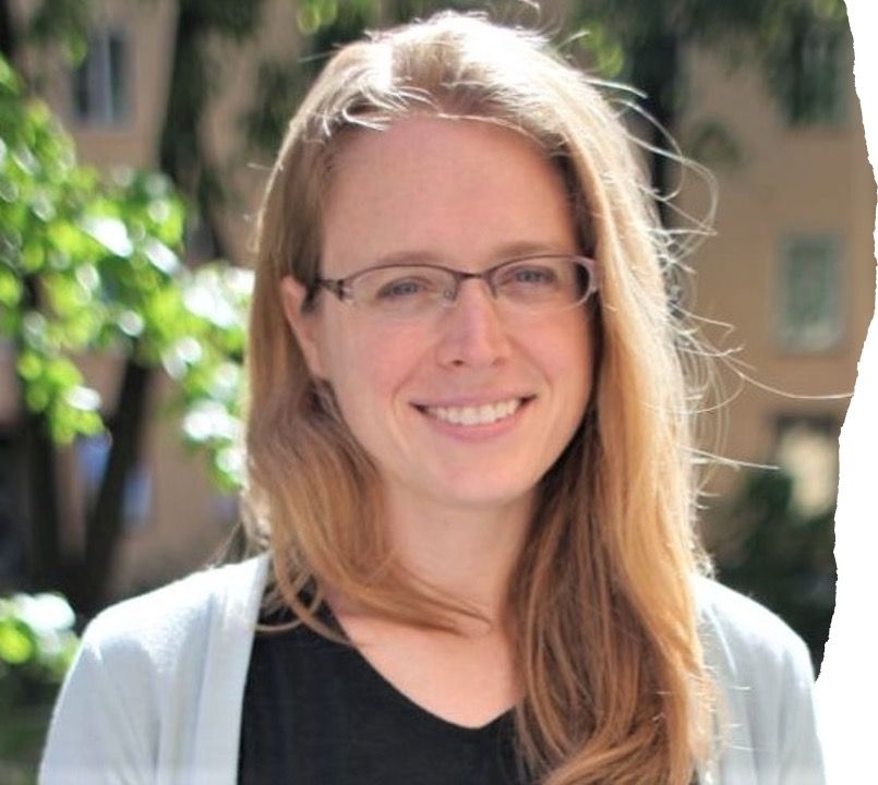 Woman with blond hair and glasses standing outside in front of a building.