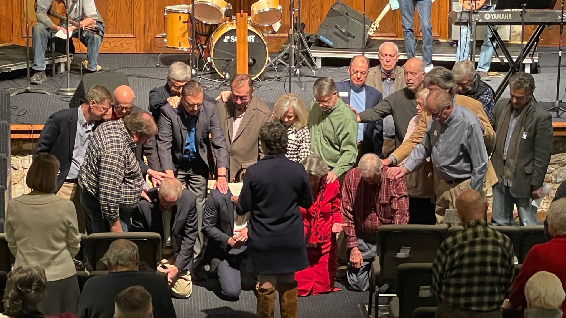 People gathered around and laying hands on four people kneeling.