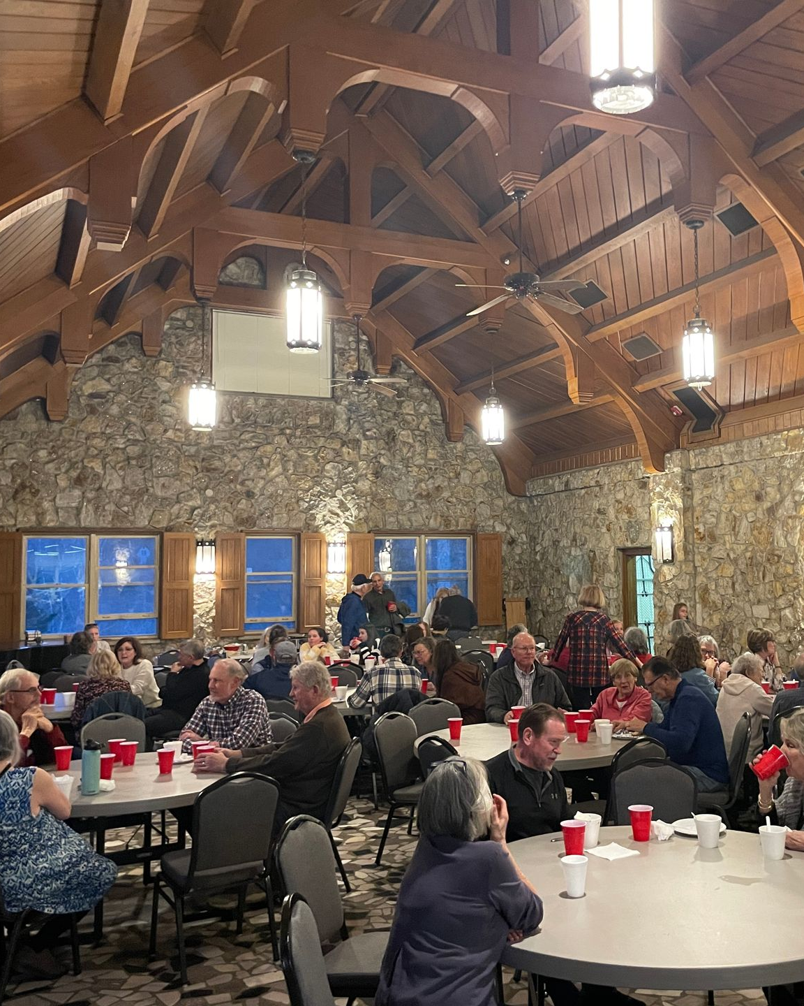 A group of people sitting around tables in a large room for a meal.