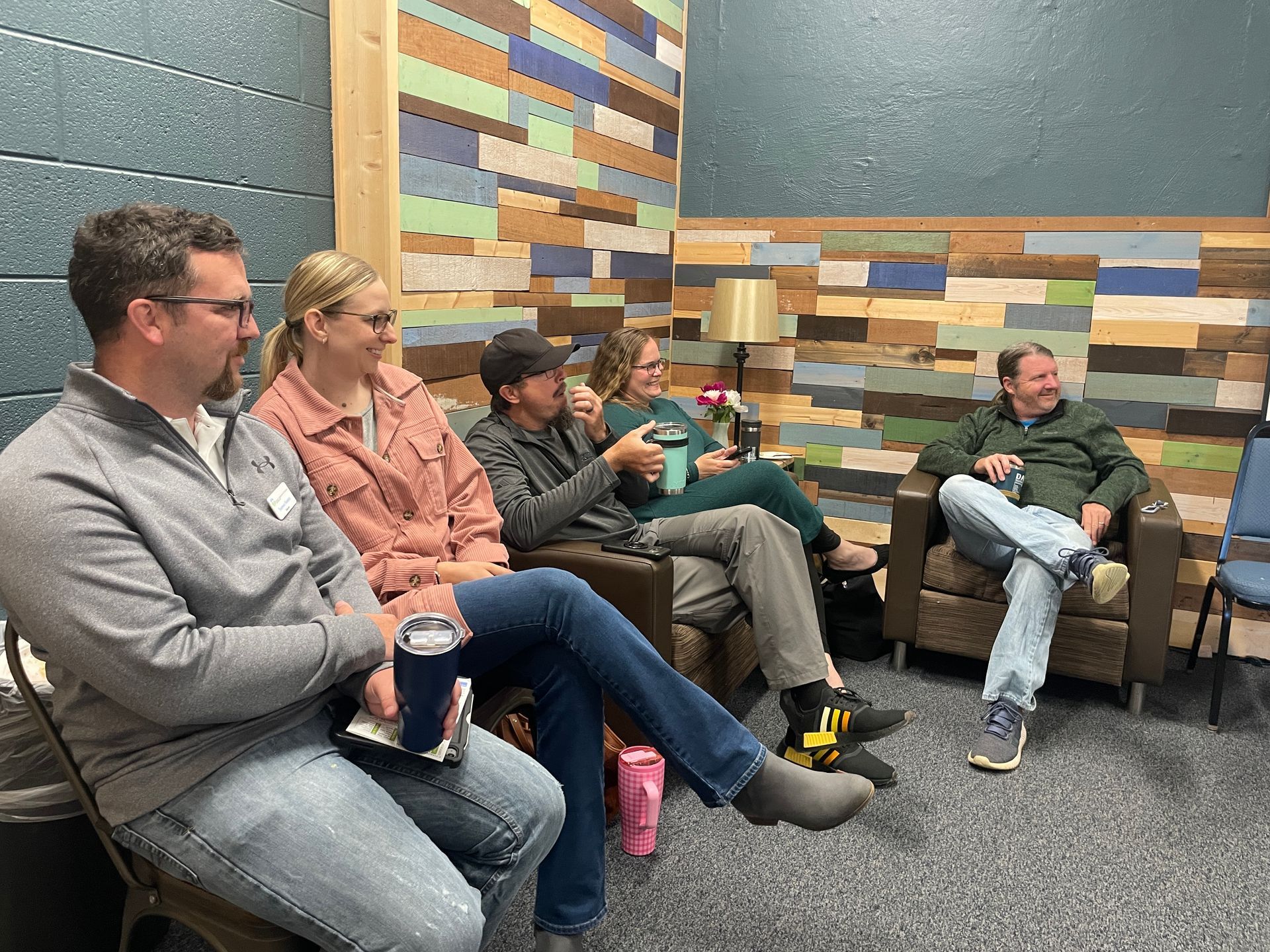 People seated in a circle in a classroom, engaged in a group discussion.