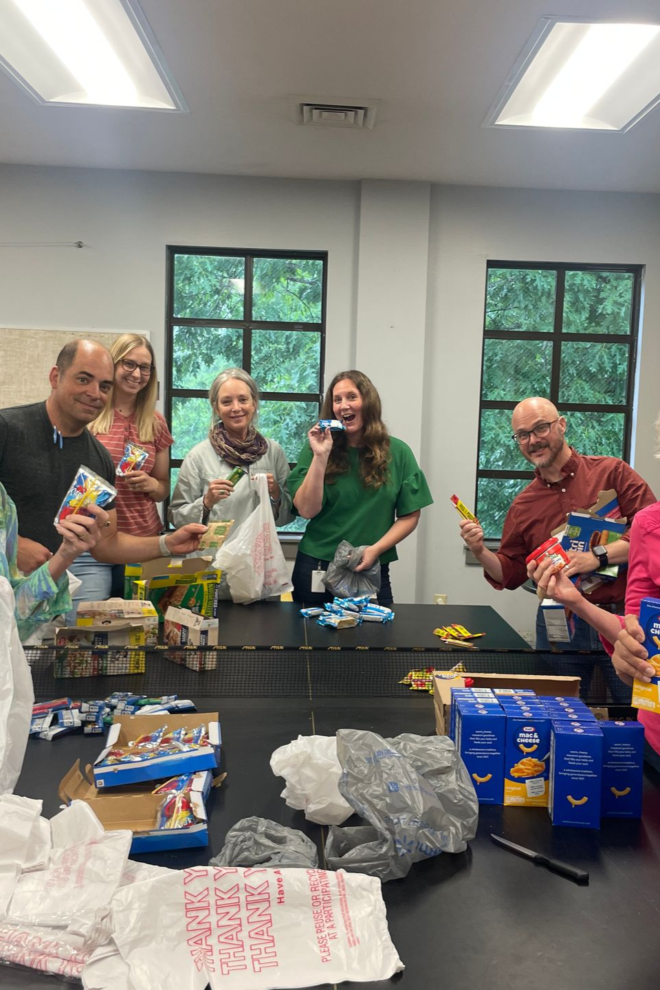 People packing food donations at a table in a bright room.