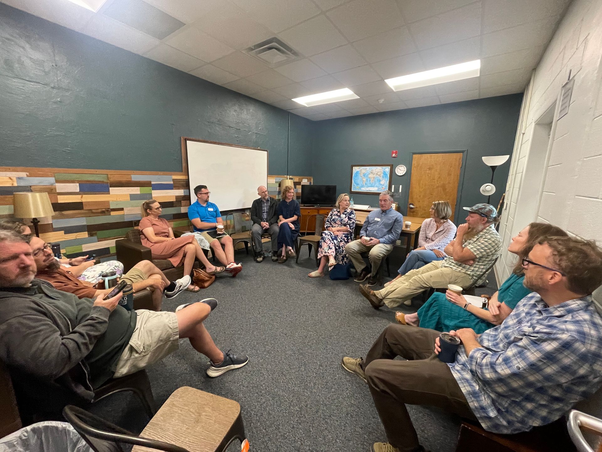 People seated in a meeting room in a circle, listening and talking during a group discussion.