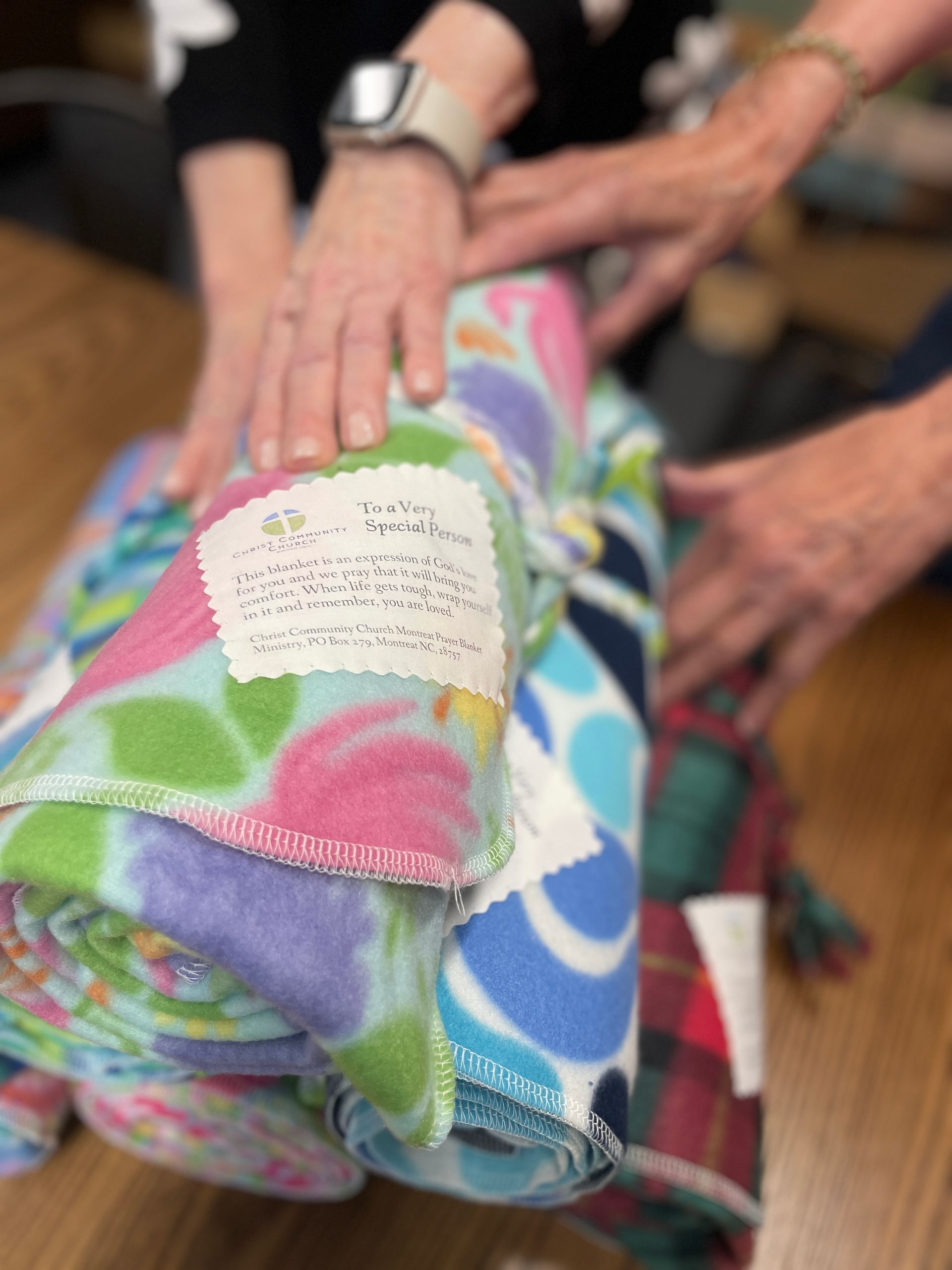 Hands touching (in prayer) colorful, patterned blankets with