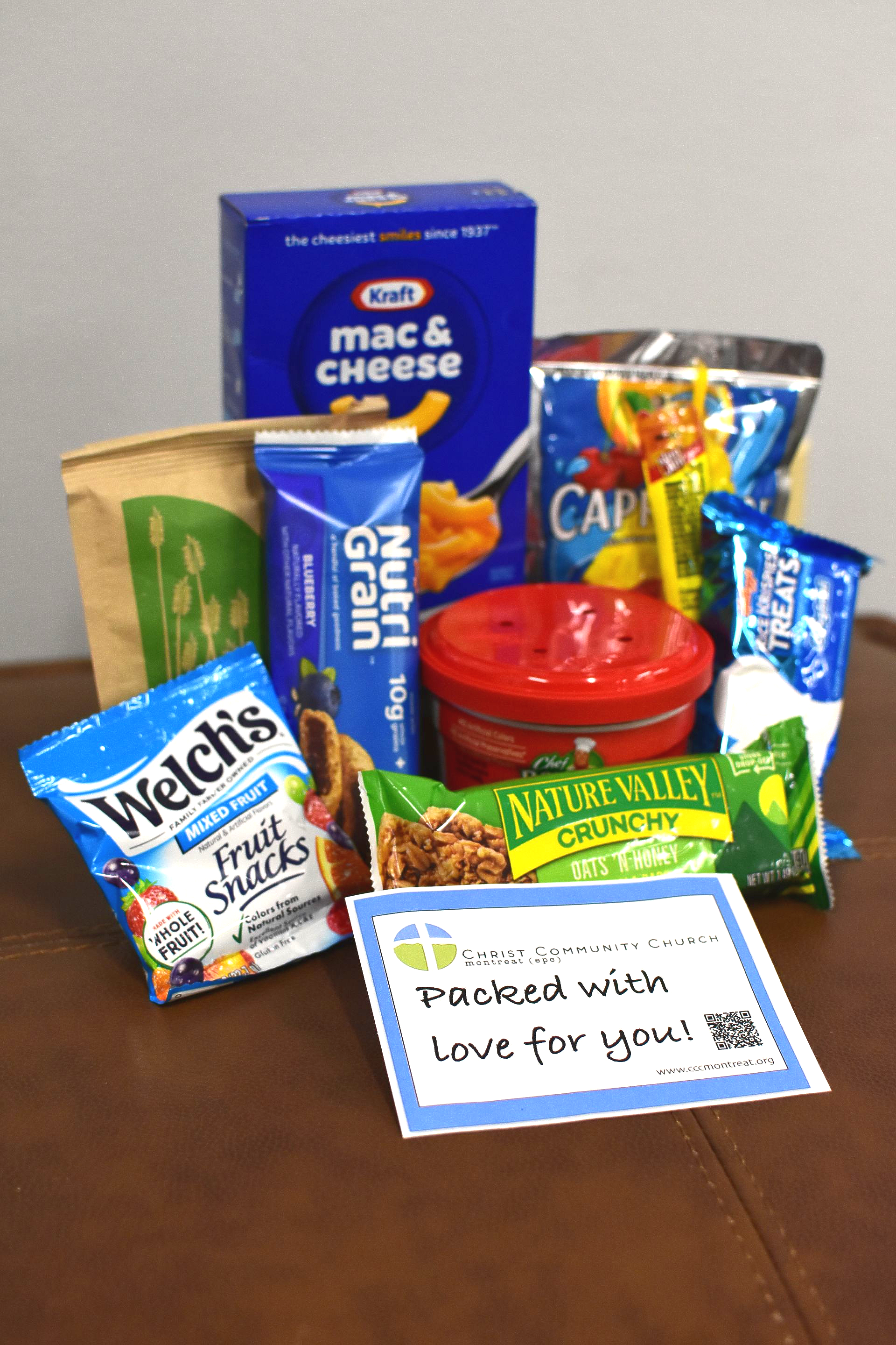 Assorted packaged snacks and a handwritten thank-you note arranged on a table.