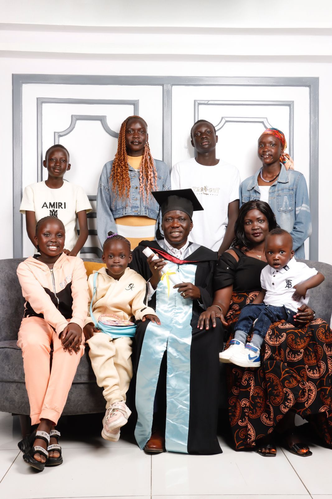 Family of nine gather around a central man in graduation regalia.