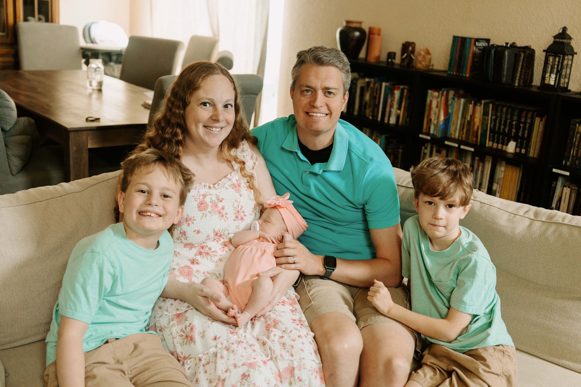 Family of five sitting on a couch in a living room.