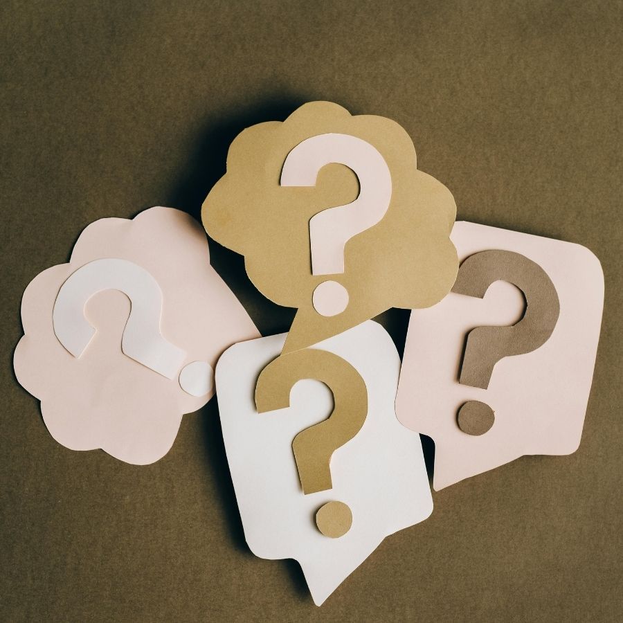 Four overlapping speech bubbles with question marks in beige, white, and gold on a brown background