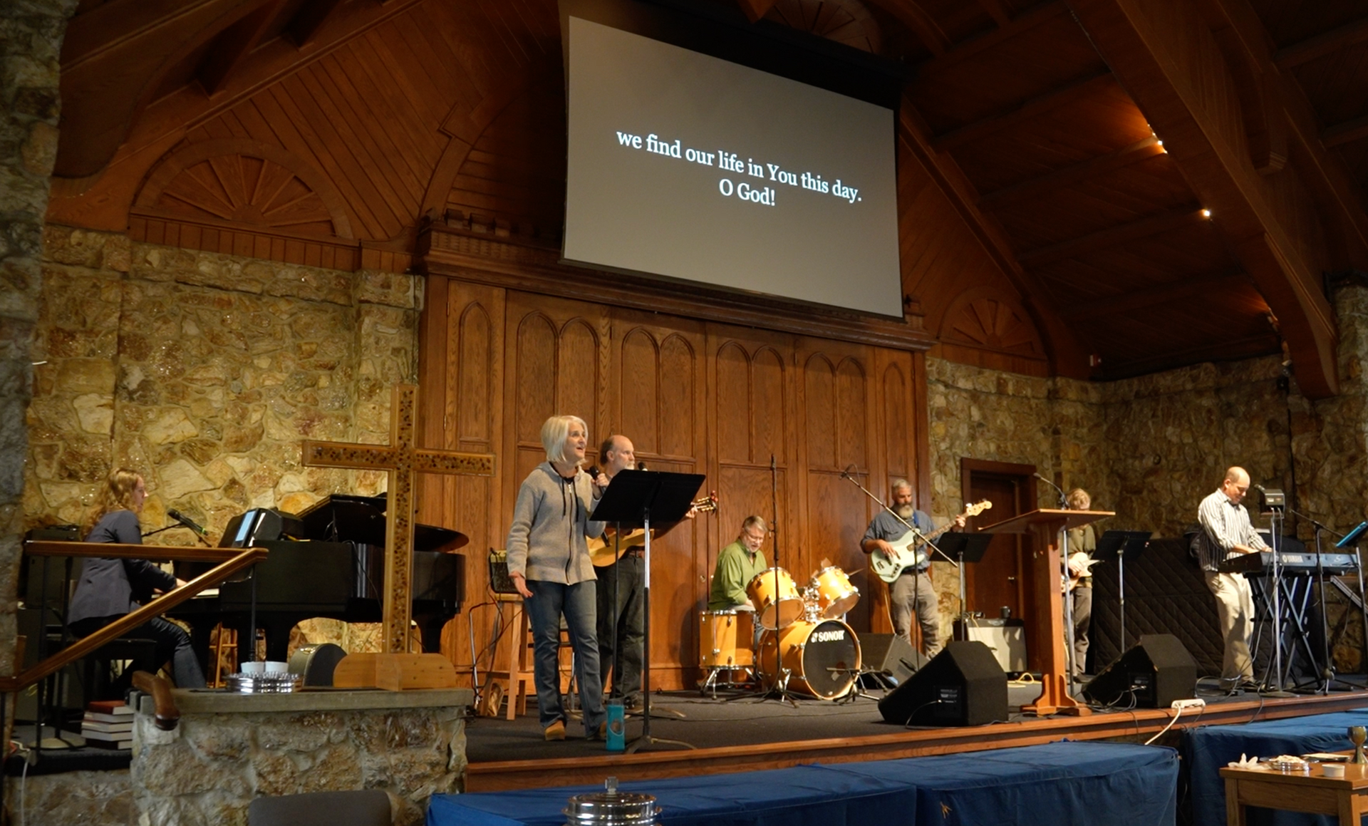 7 person praise band leading songs in a stone building with wooden accents.