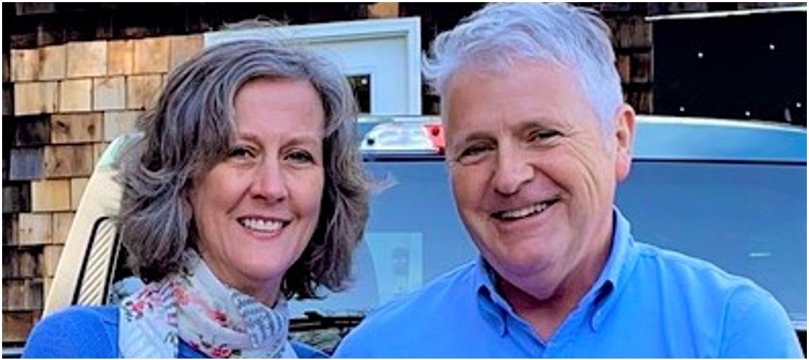 Man and woman standing outside in front of a car.