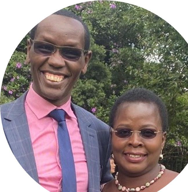 Man and woman in sunglasses standing in front of greenery.
