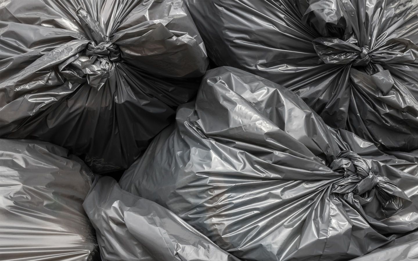 A pile of black rubbish bags are stacked on top of each other.