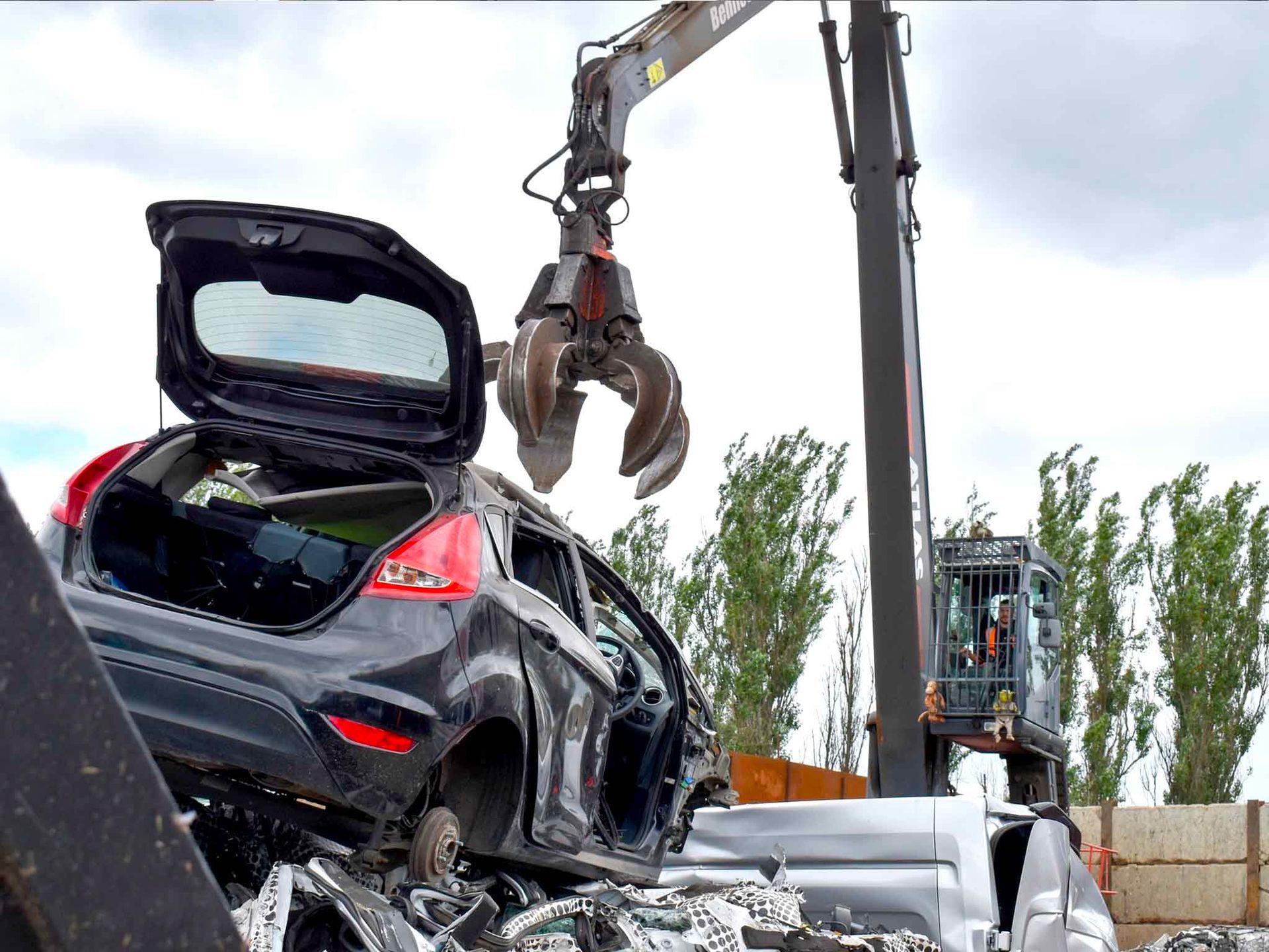 Scrap car metal claw picking up scrap car