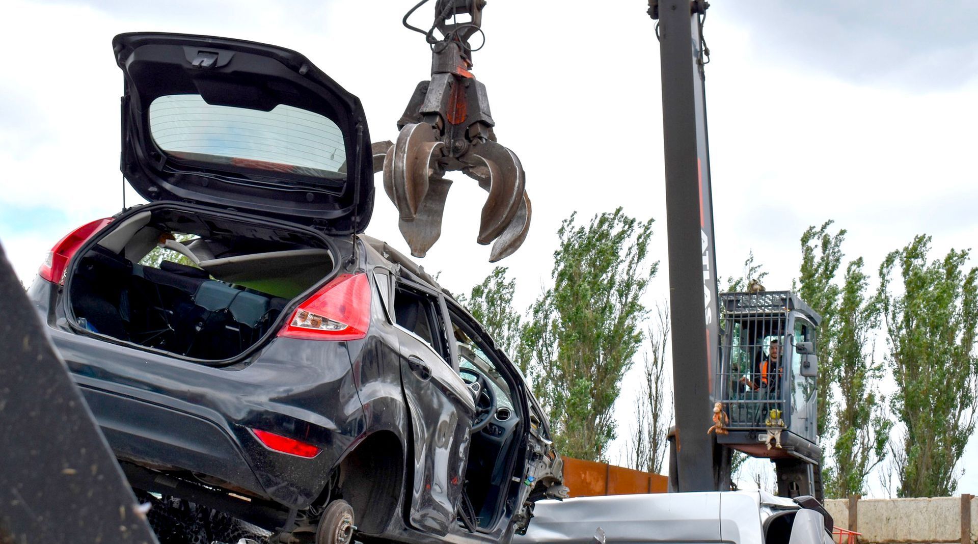 A black car is being dismantled by a claw at Benfleet Scrap yard