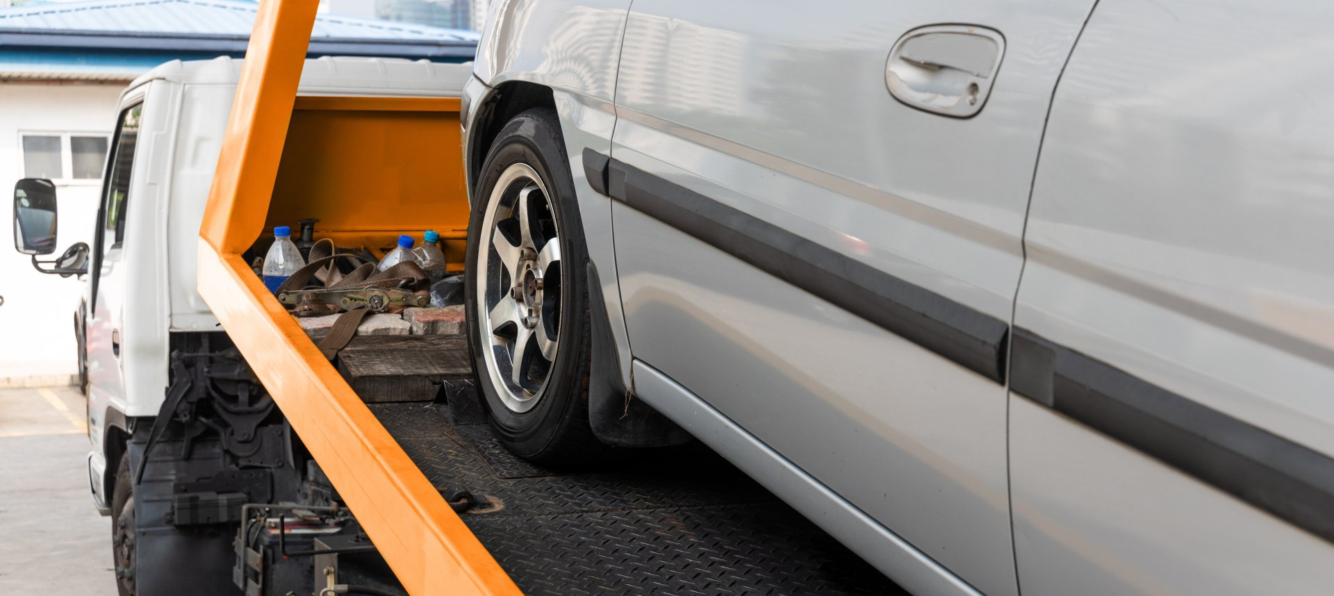 A silver car is being towed by a Benfleet Scrap tow truck.