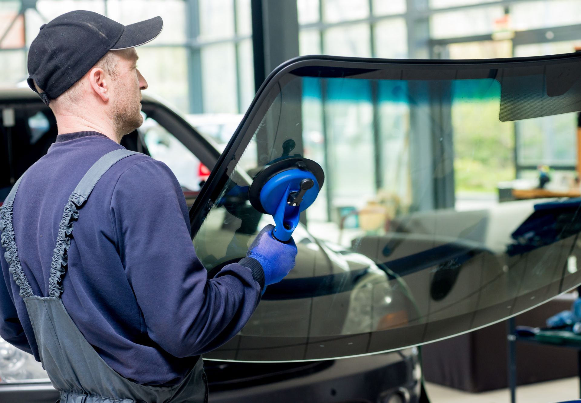 Technician using a blue suction tool to repair a cracked car windshield