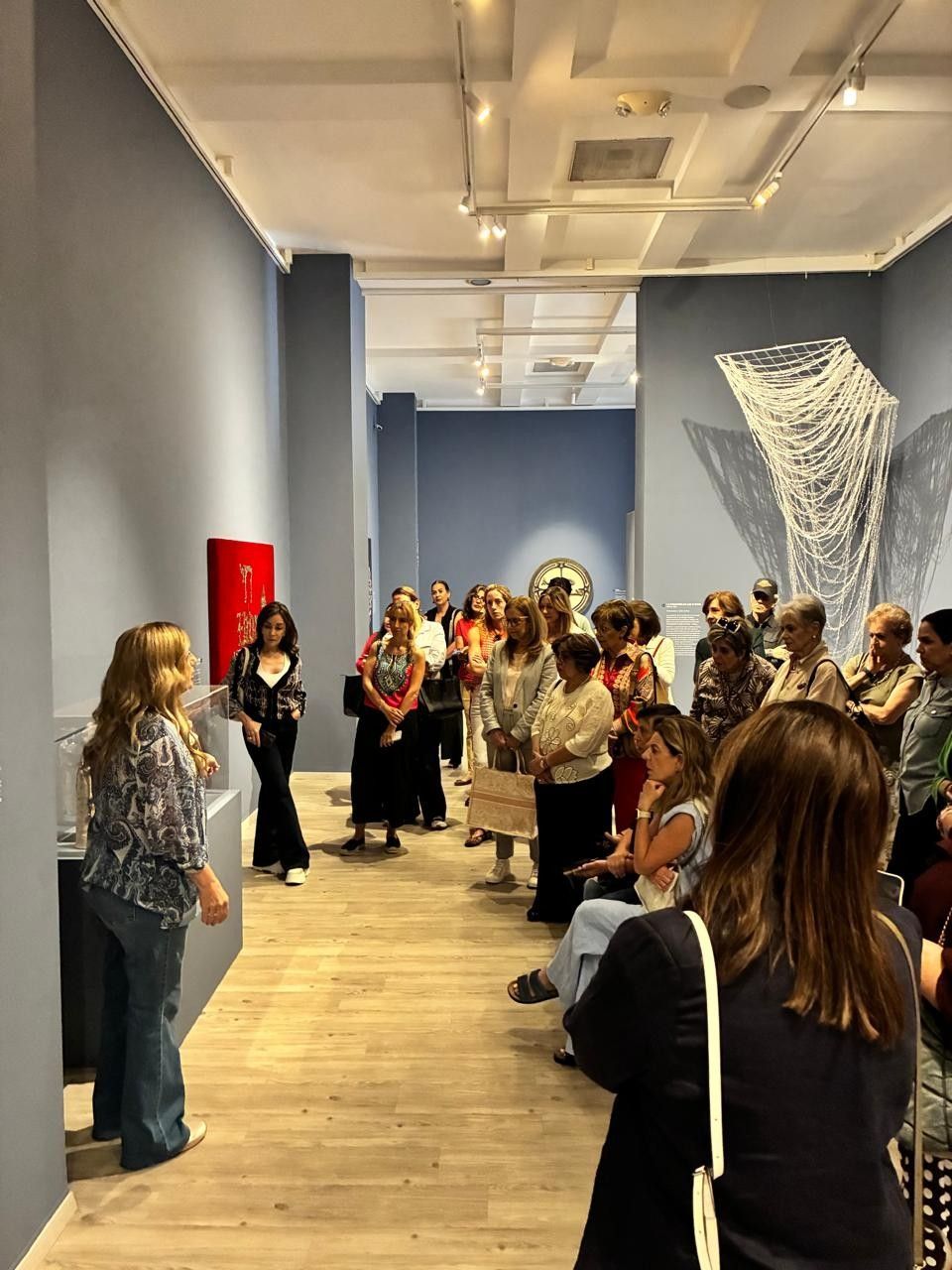 La gente se congregó en el pasillo de la galería, muchos con sus teléfonos o cámaras en la mano, cerca de las obras de arte expuestas en las paredes.