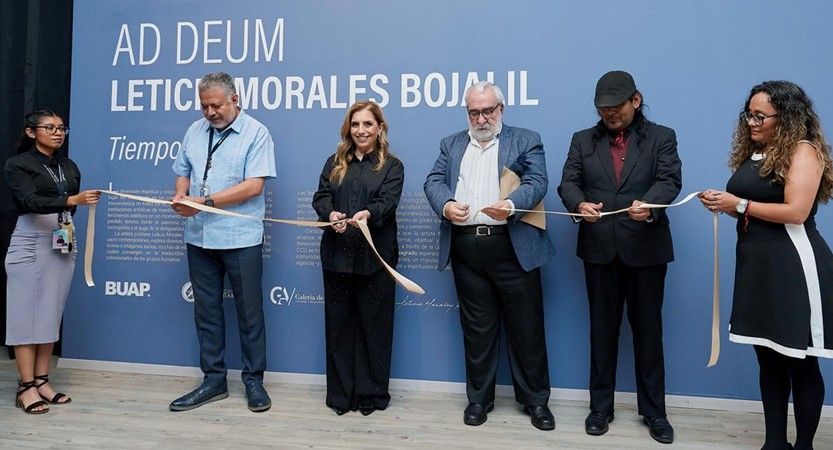 Personas de pie en una ceremonia de corte de cinta frente a un telón de fondo azul para el evento.