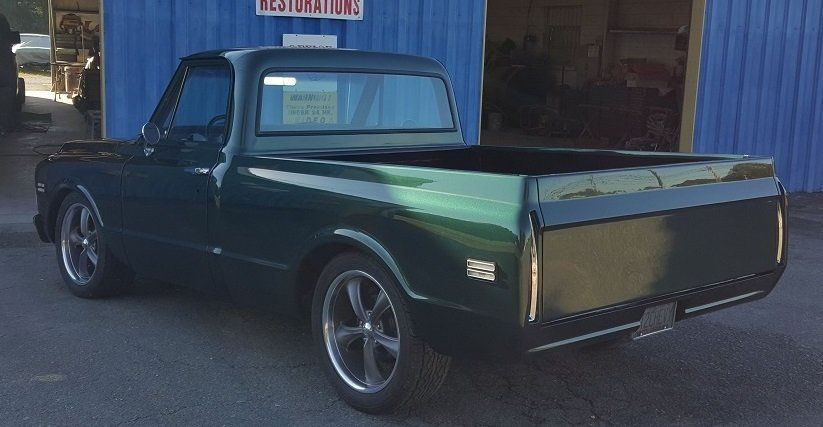 A green truck is parked in front of a blue building