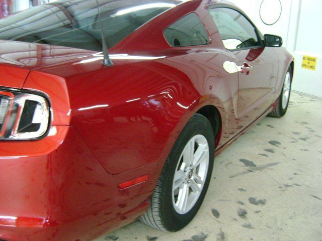 A red ford mustang is parked in a garage