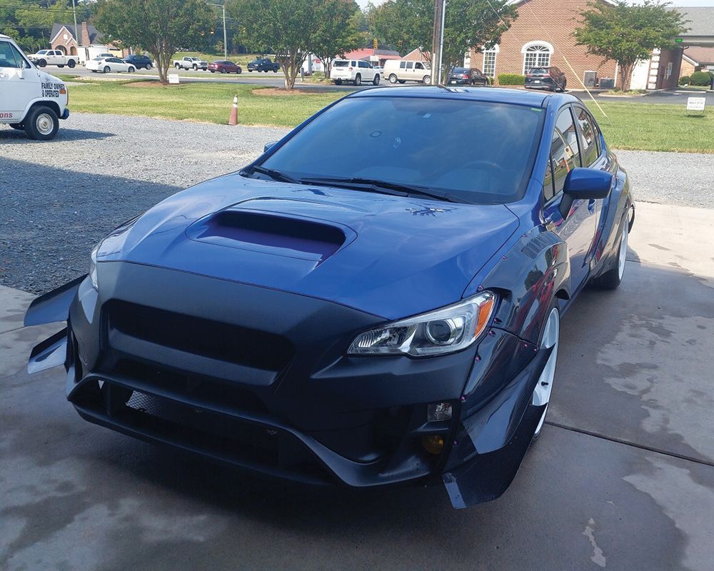 A blue car is parked in front of a brick building.