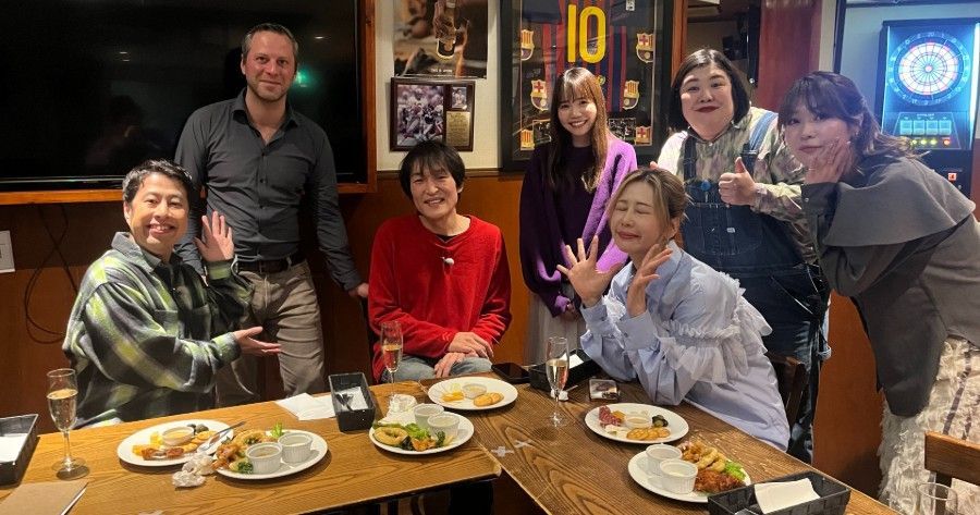 A group of people are standing around a table with plates of food.