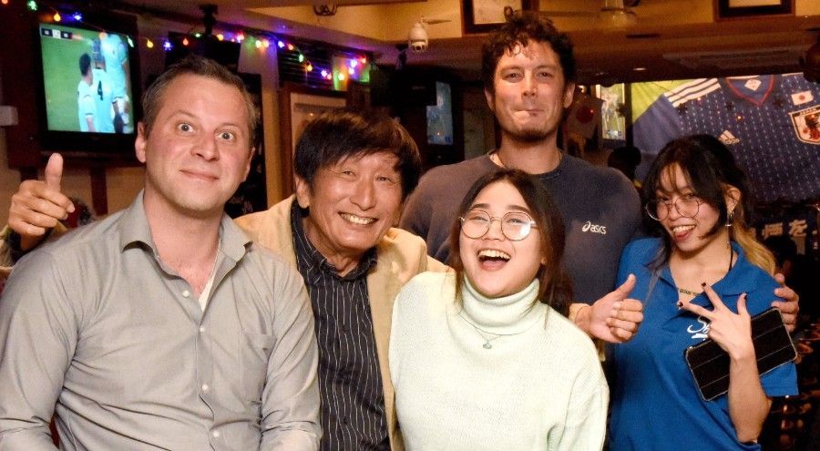 Um grupo de pessoas está posando para uma foto em um bar.