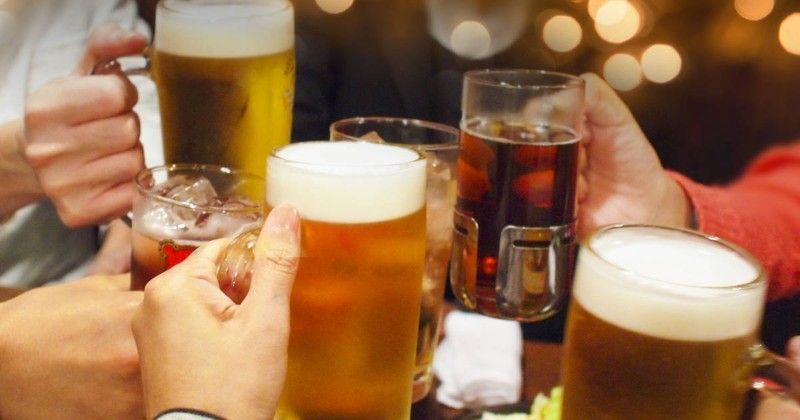 一群の人々がビールを片手に乾杯している。