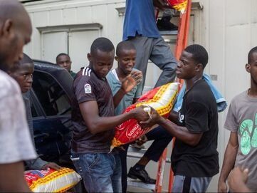 A group of people loading large, red and yellow bags of supplies into a vehicle.