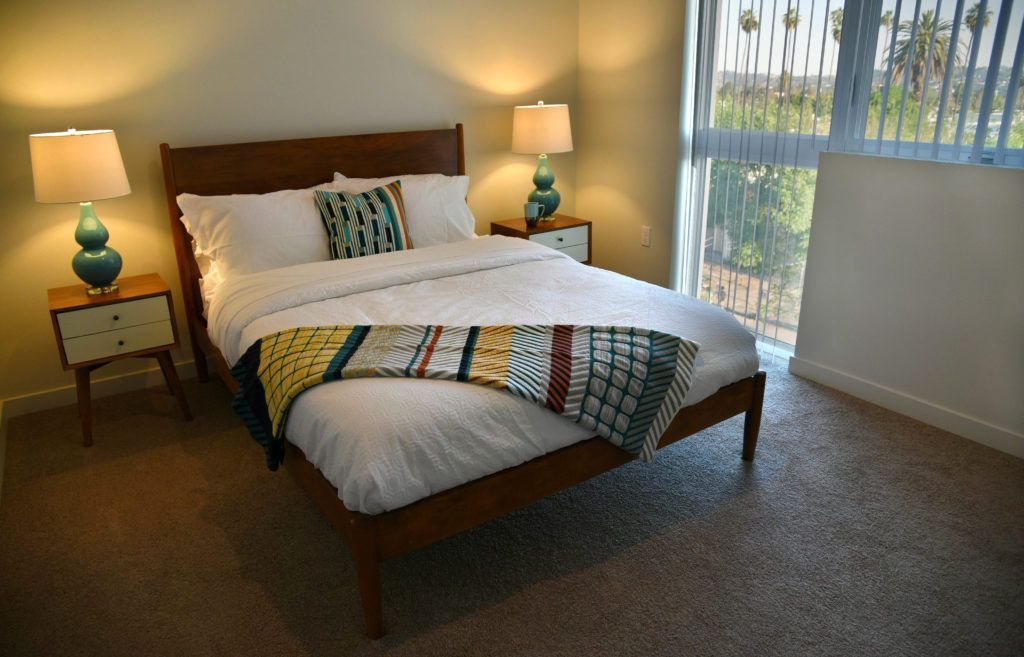 A bedroom with a bed , two lamps and a window.