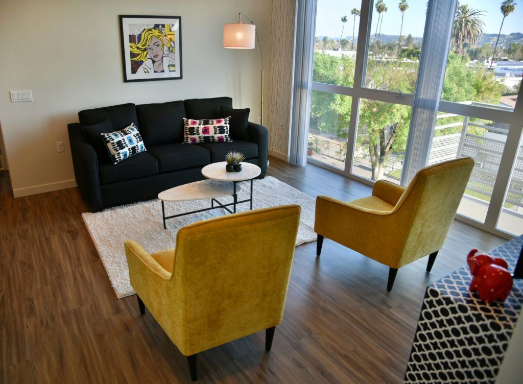 A living room with a black couch and yellow chairs