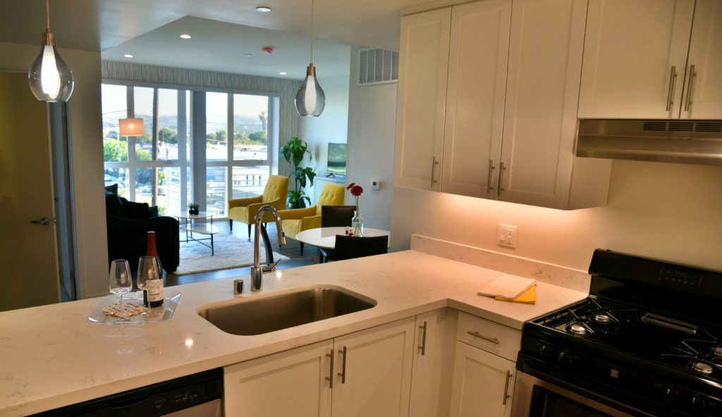 A kitchen with white cabinets and a stainless steel sink