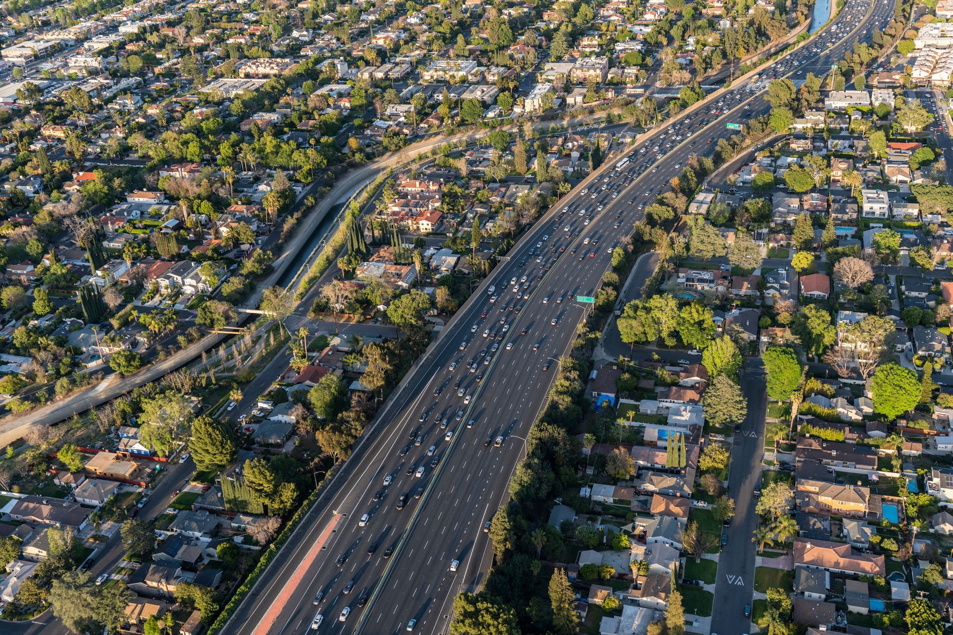 An aerial view of a highway going through a residential area.