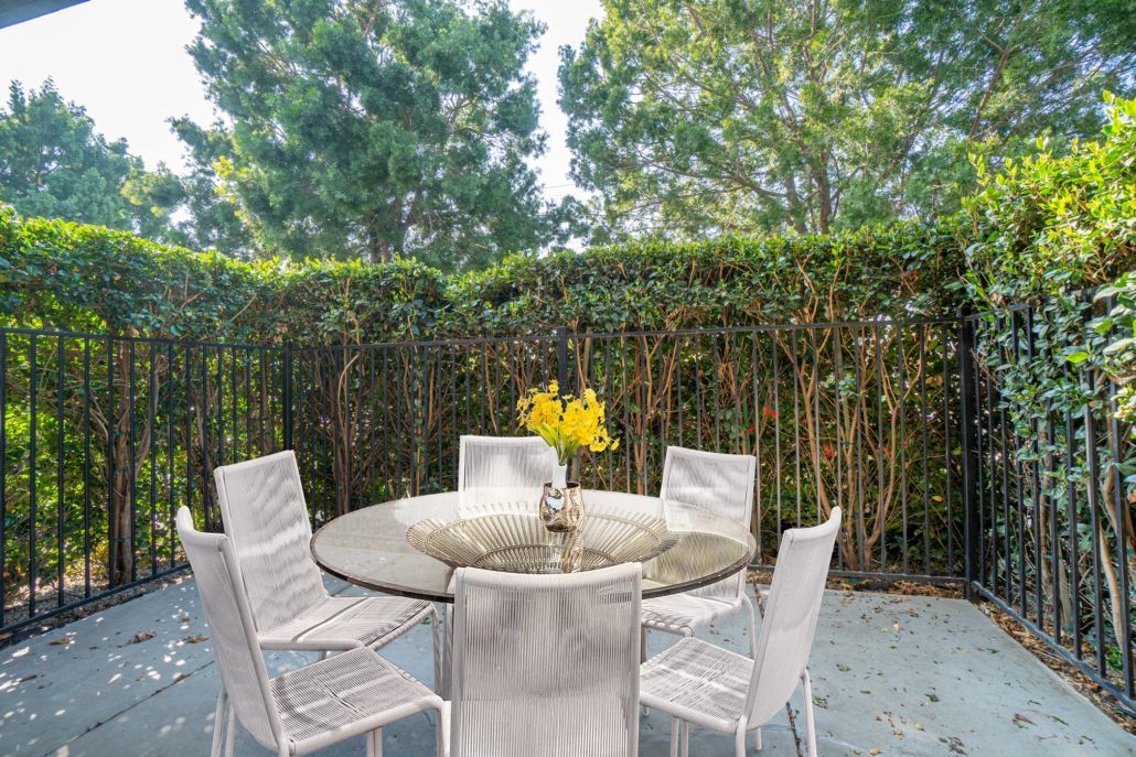 A patio with a table and chairs and a vase of flowers.