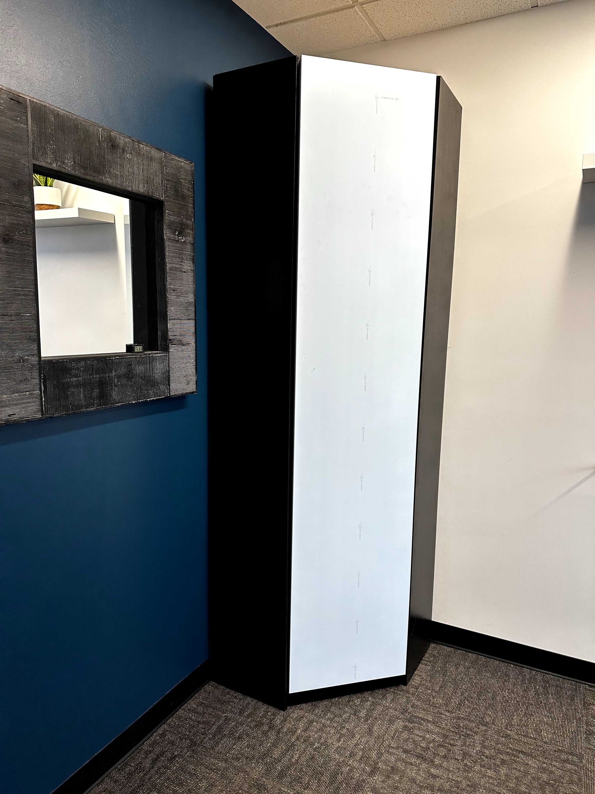 A room with a black and white cabinet and a mirror on the wall.