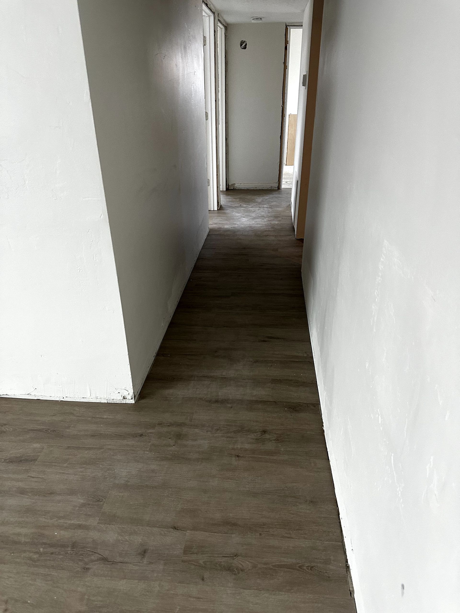 A long hallway with a wooden floor and white walls.