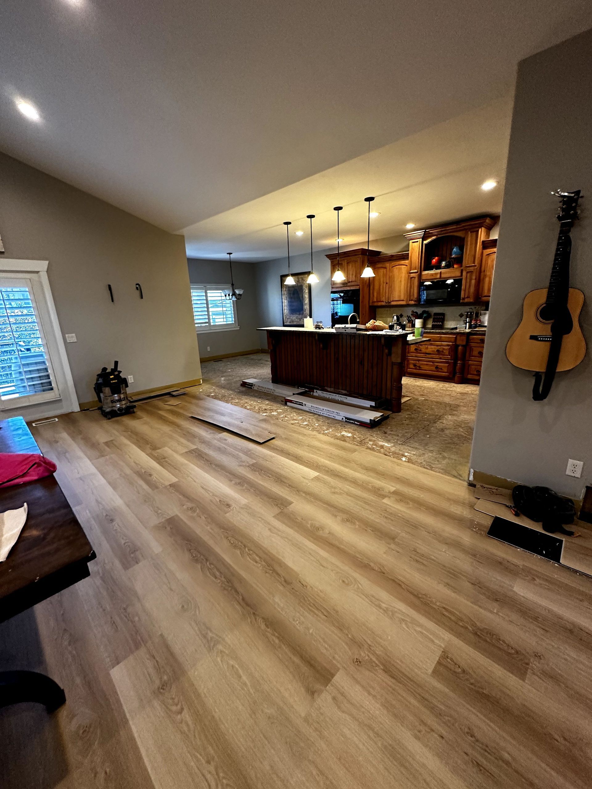 A living room with hardwood floors and a guitar hanging on the wall.