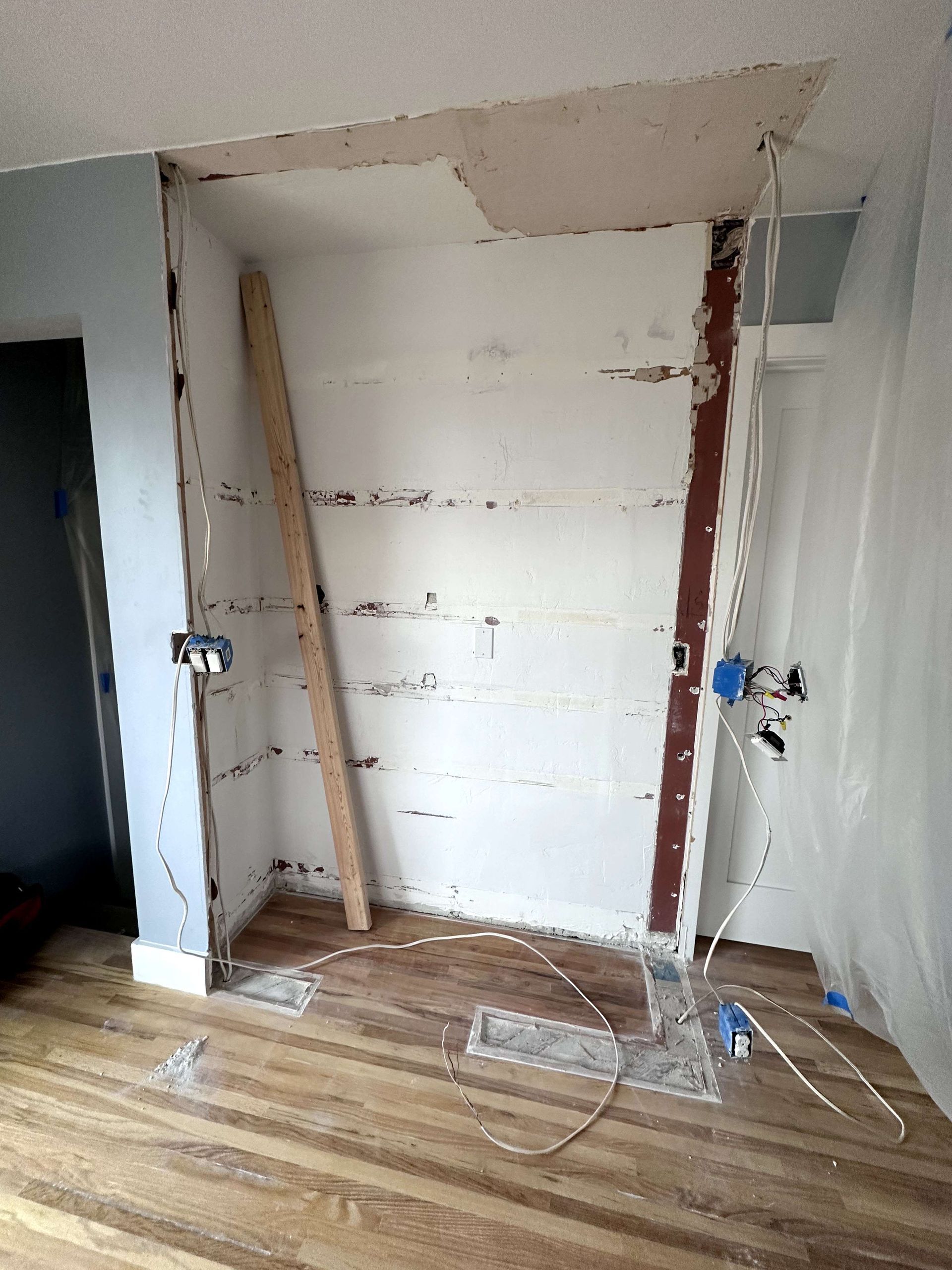 A room with a wooden floor and a wall that is being remodeled.