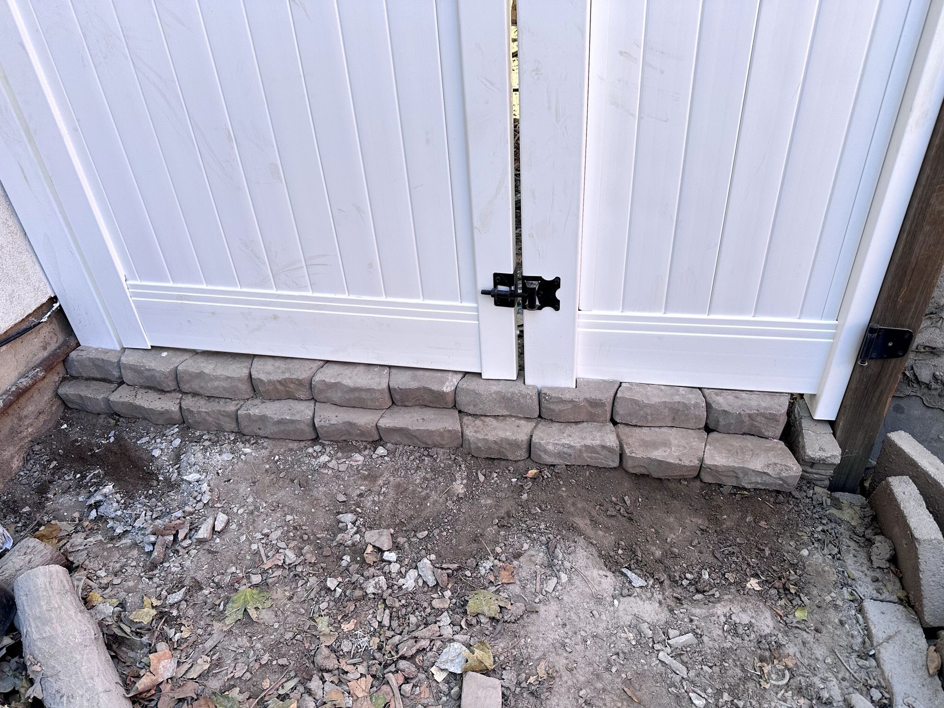A white fence is sitting on top of a pile of bricks.
