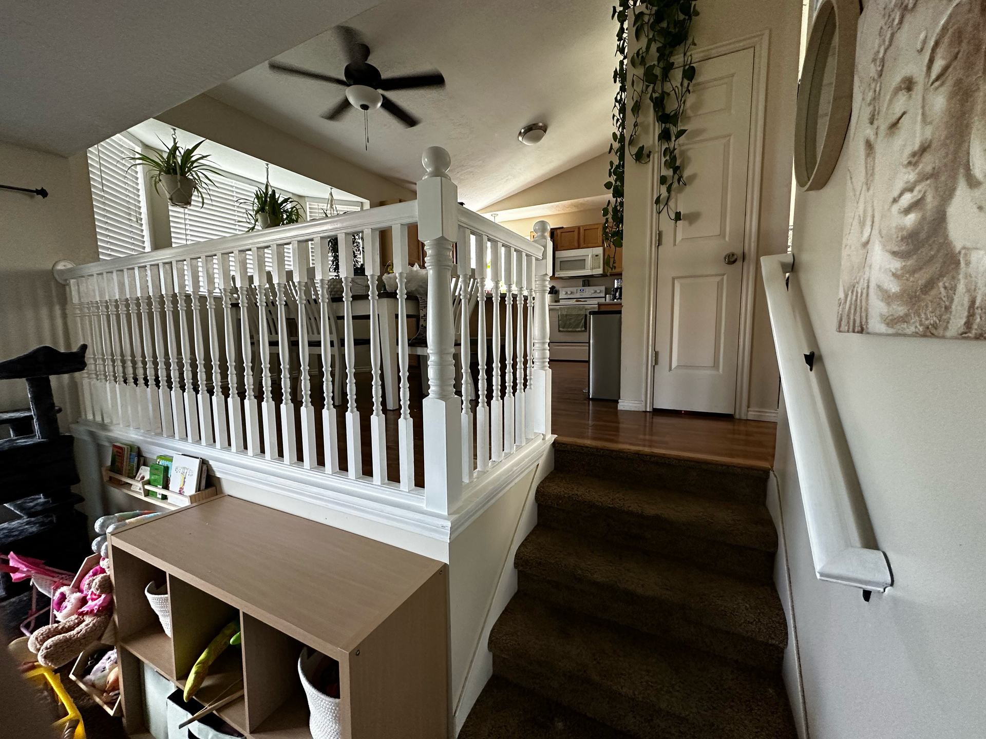 A staircase in a house with a white railing and a ceiling fan.