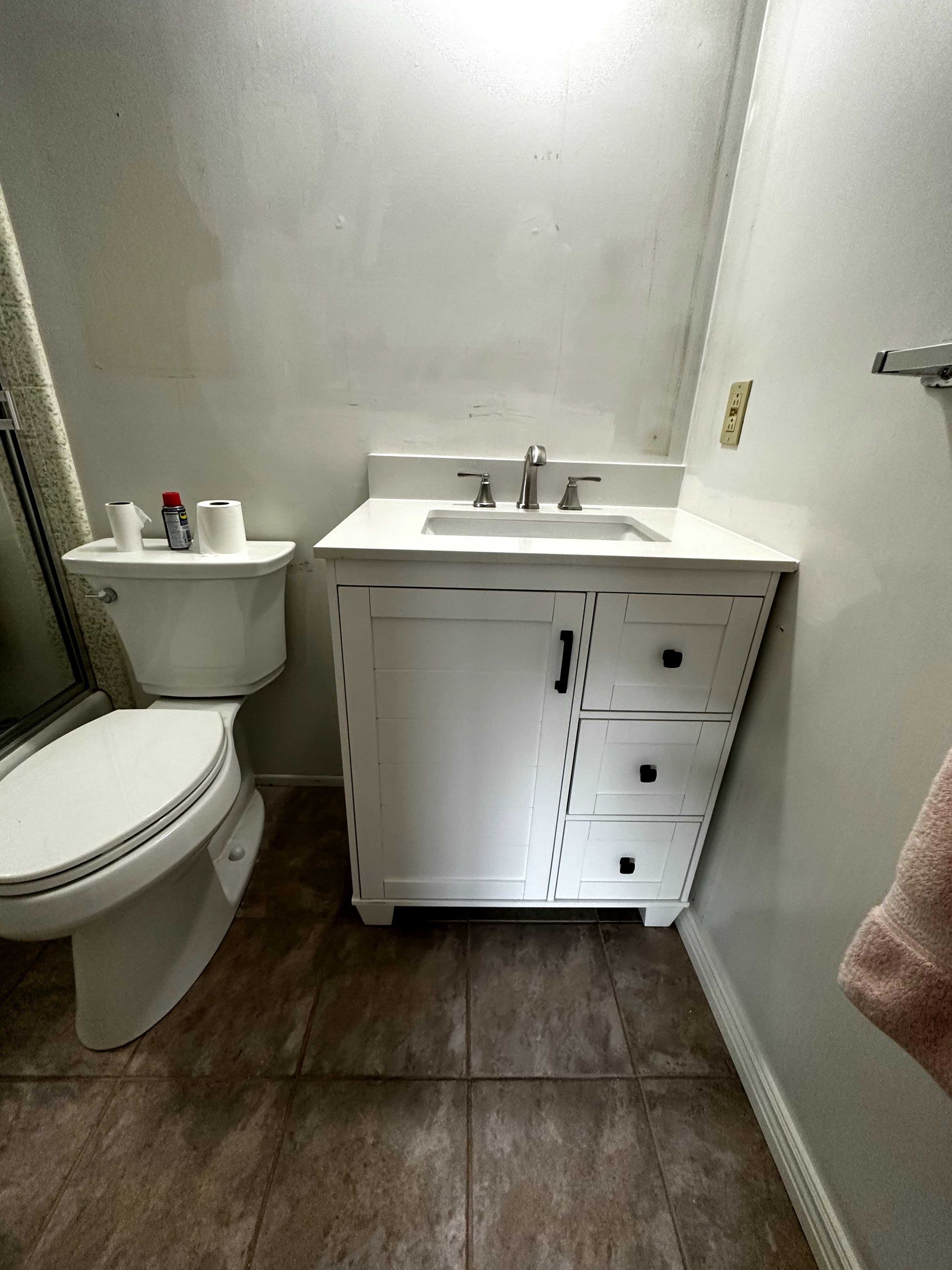 A bathroom with a toilet , sink and mirror.