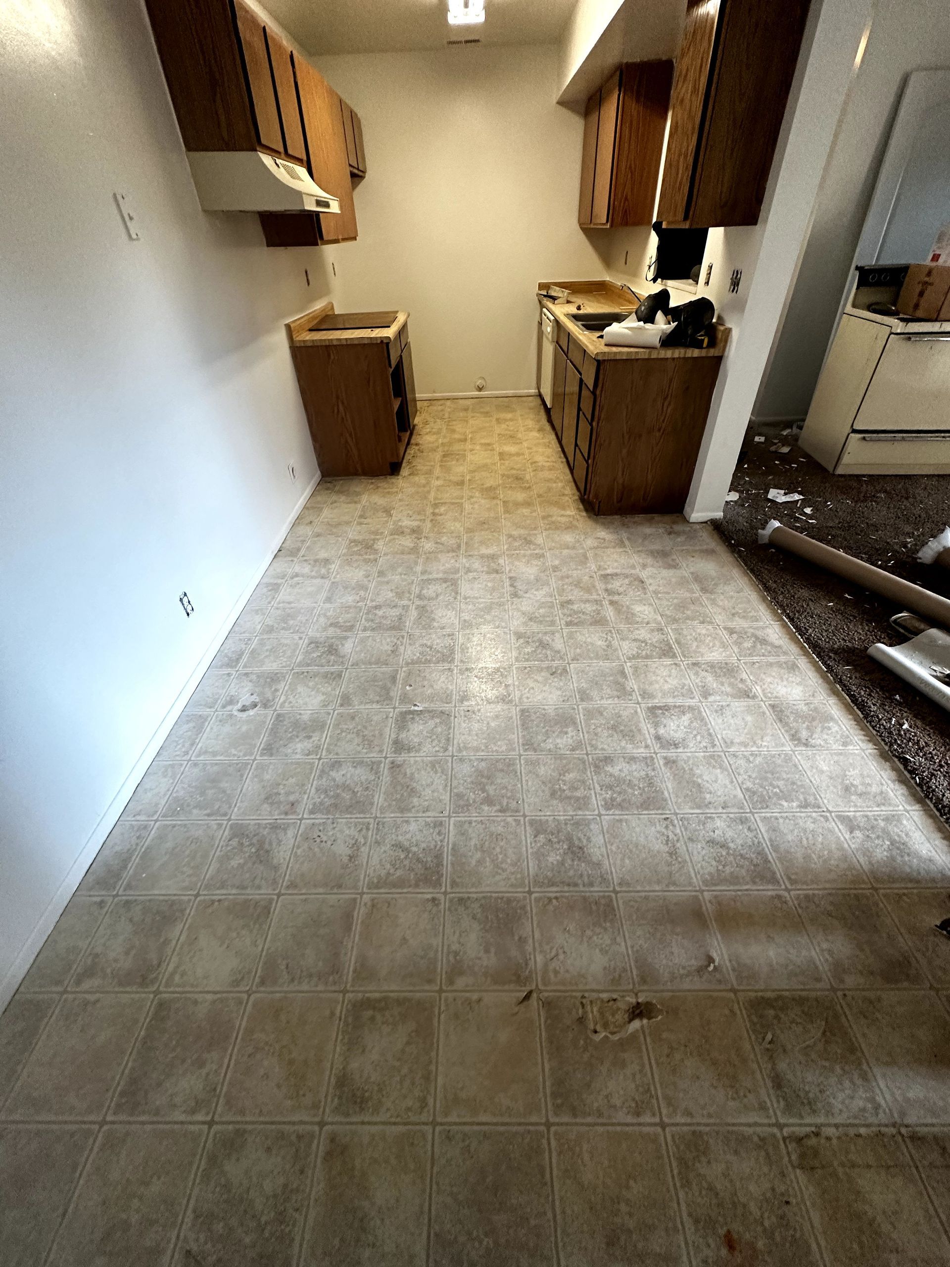 A kitchen with a tile floor and wooden cabinets.